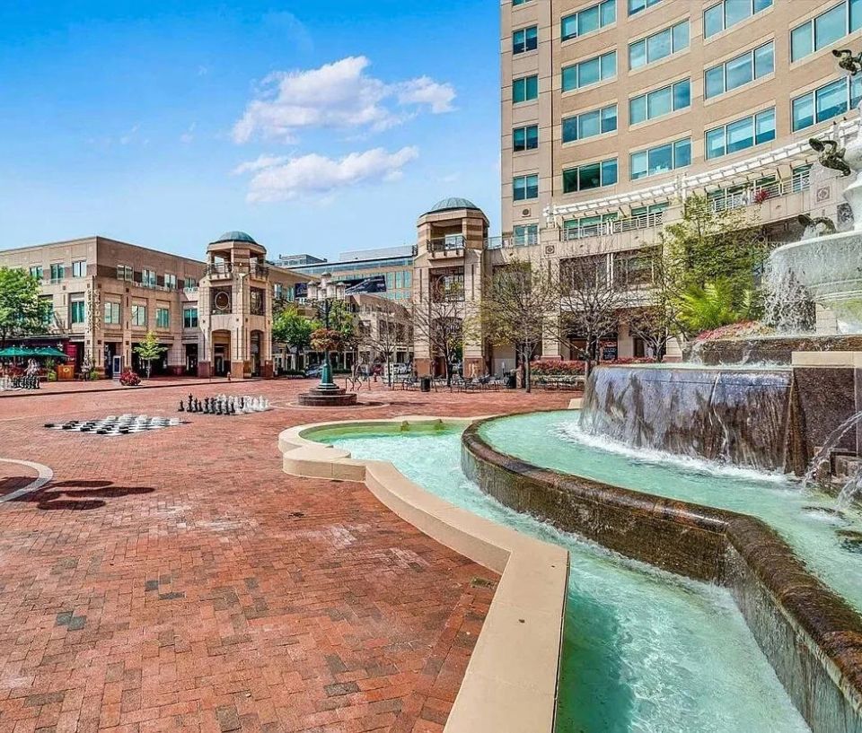 Brick plaza with a large fountain surrounded by shops and buildings in Reston, Virginia.